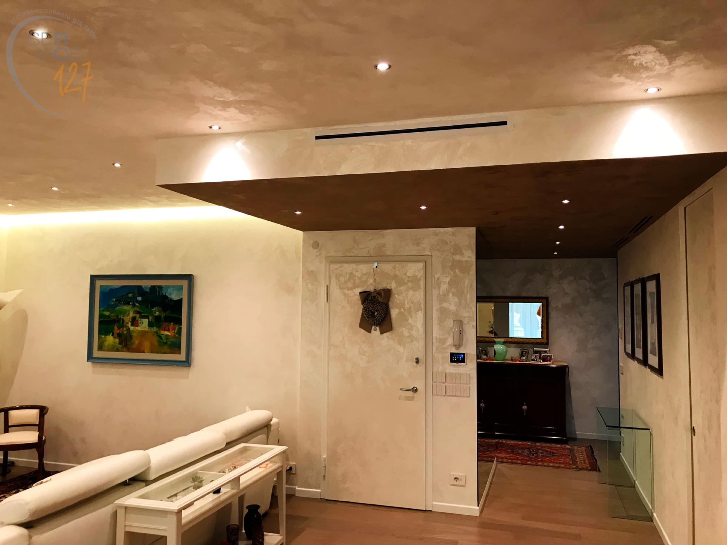 Soggiorno con controsoffitto illuminato e pareti in stucco