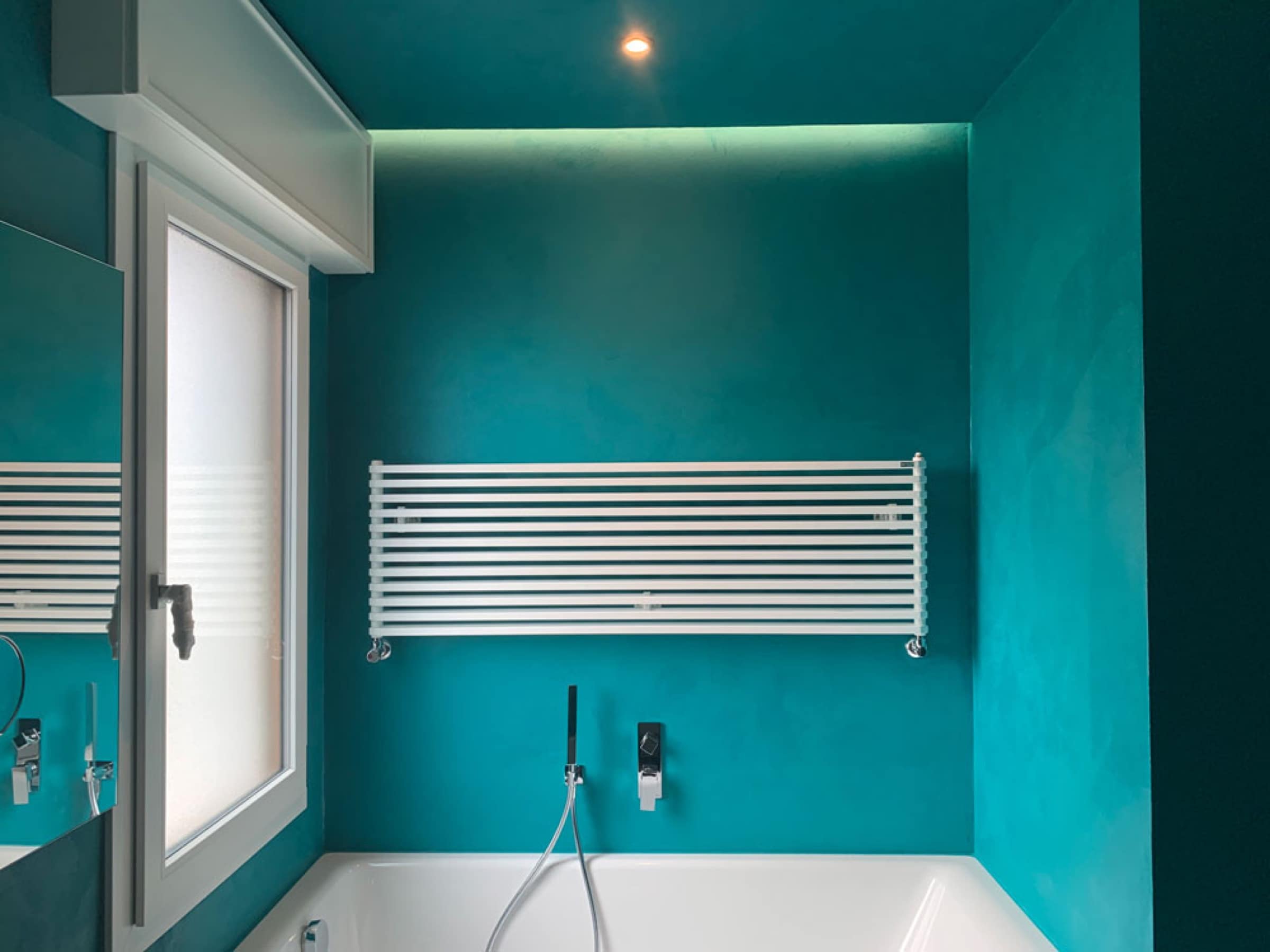Bagno con parete color petrolio e vasca