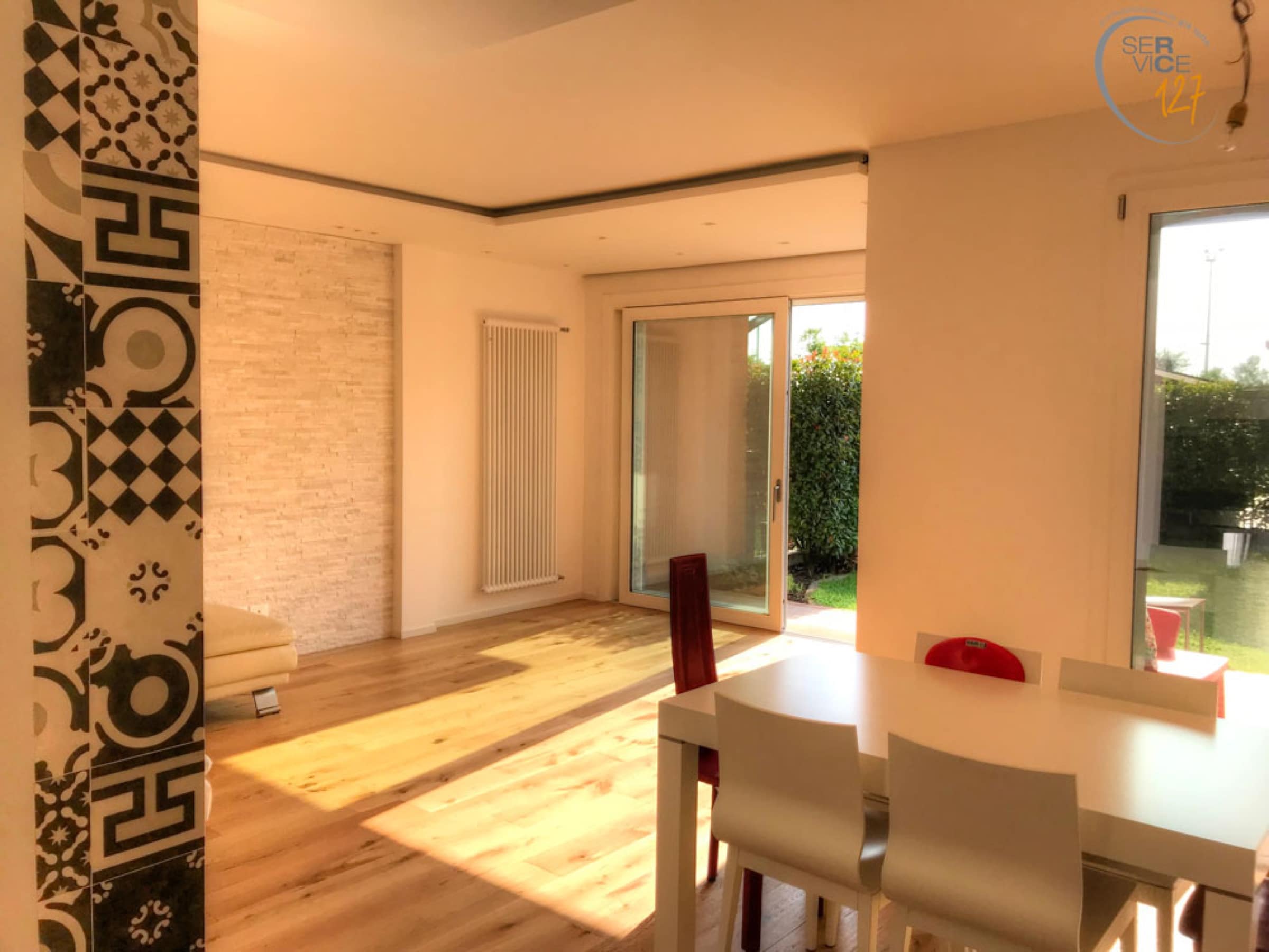 Zona giorno luminosa con pavimento in legno e parete decorata