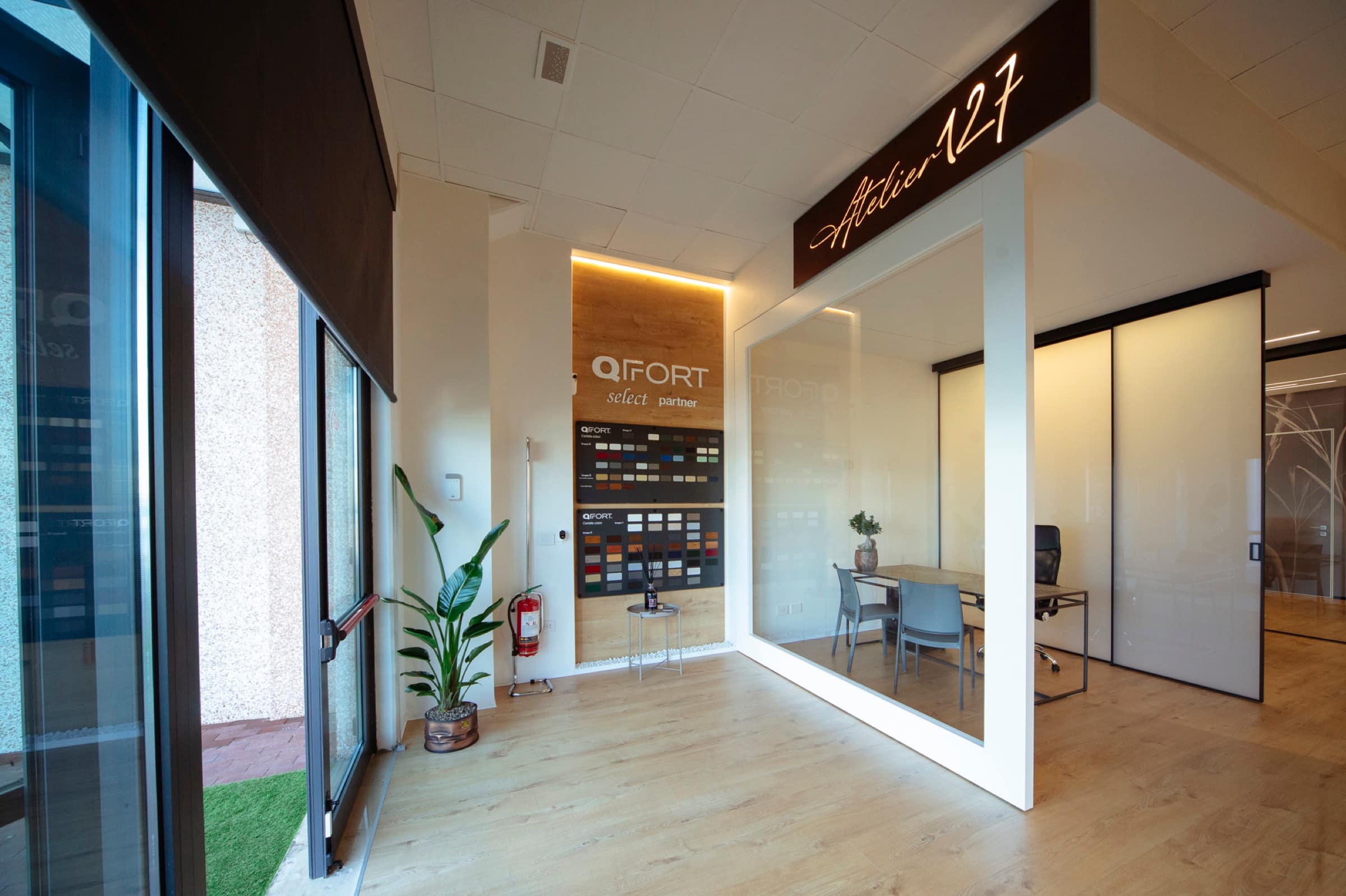 Ingresso dell'Atelier127 con l'insegna luminosa e la sala riunioni vetrata