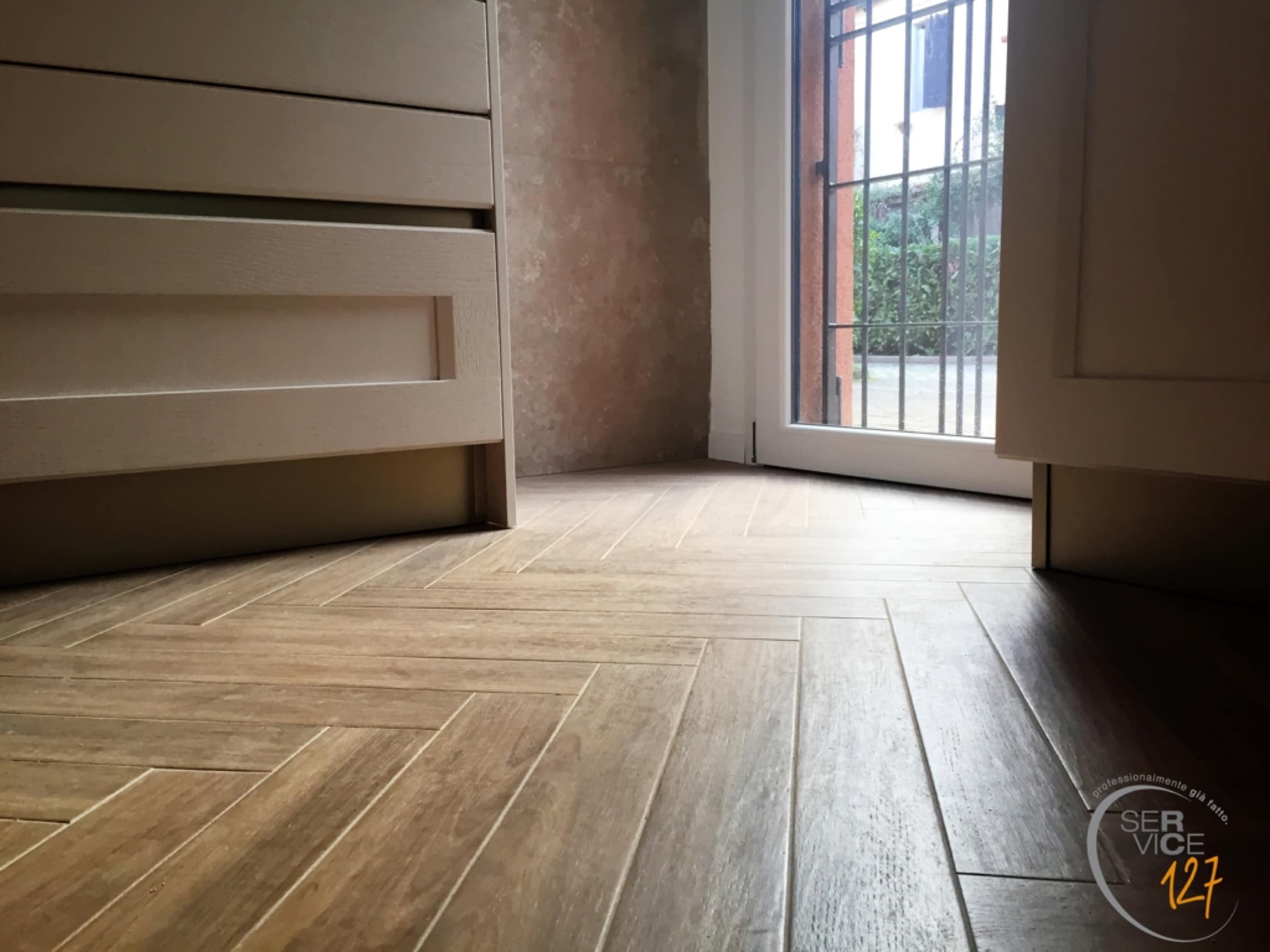 Pavimento in legno a spina di pesce davanti a una portafinestra